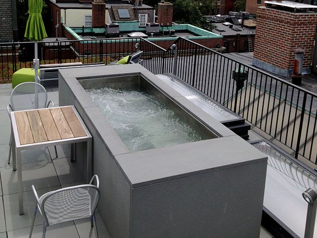 A rooftop patio with a table and chairs and a hot tub