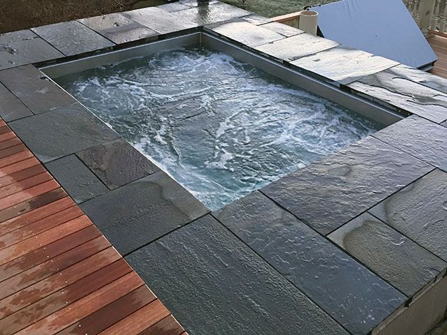 A swimming pool surrounded by tiles on a wooden deck.