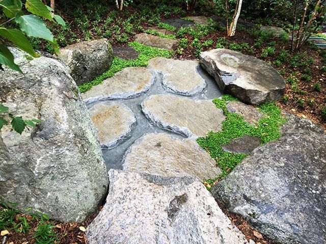 A stone walkway surrounded by rocks and grass in a garden.
