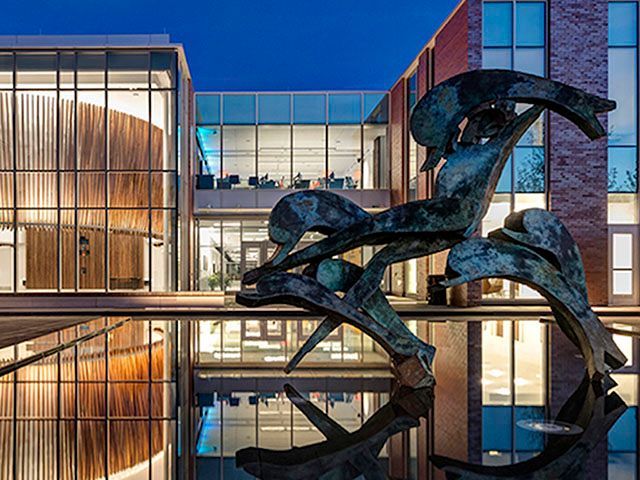 A large sculpture is in front of a building with a lot of windows.