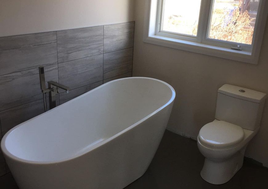 Une salle de bain avec baignoire, WC et fenêtre.