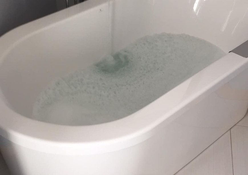 Une baignoire remplie d'eau et de mousse dans une salle de bain.