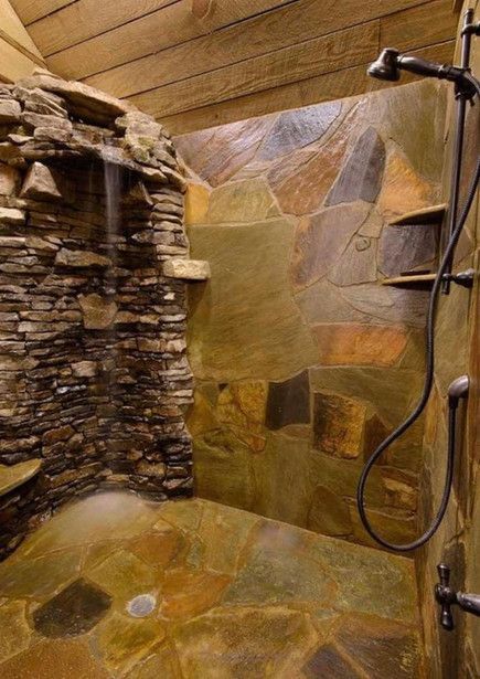 Une douche avec un mur en pierre et une pomme de douche.