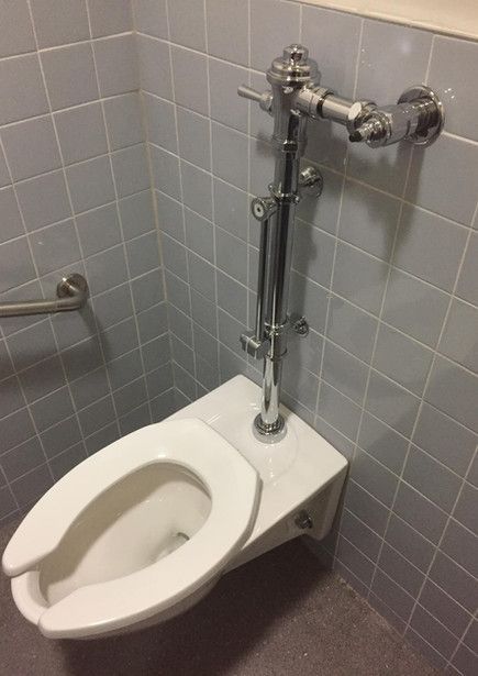 Une toilette blanche est installée dans une salle de bain à côté d'un urinoir.