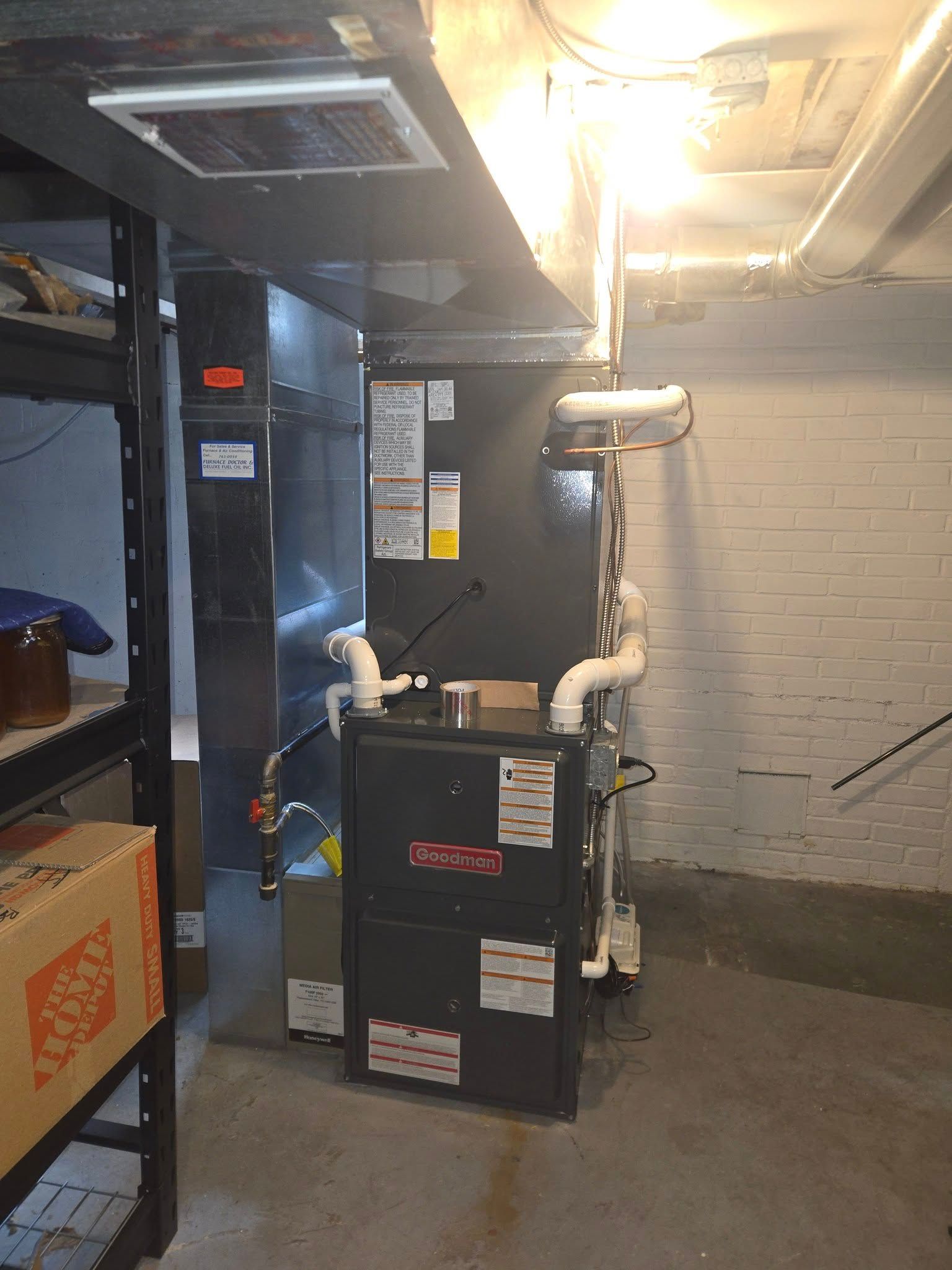 Furnace in a basement, black and gray with white pipes.