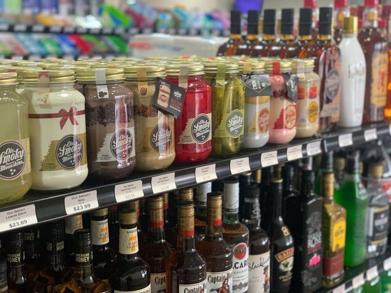 A shelf filled with bottles of liquor and jars of pickles.