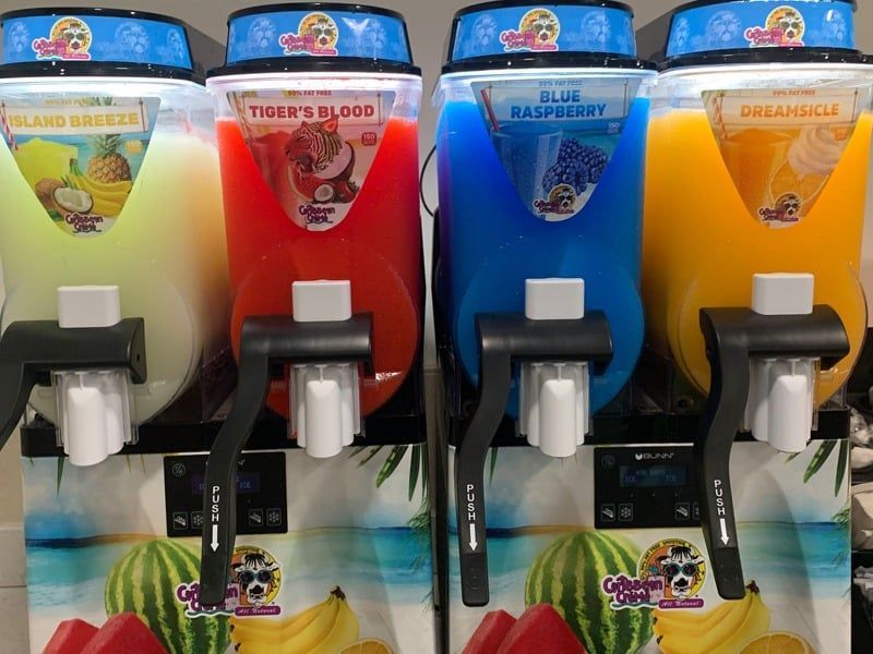 A row of slushy machines with different flavors on them