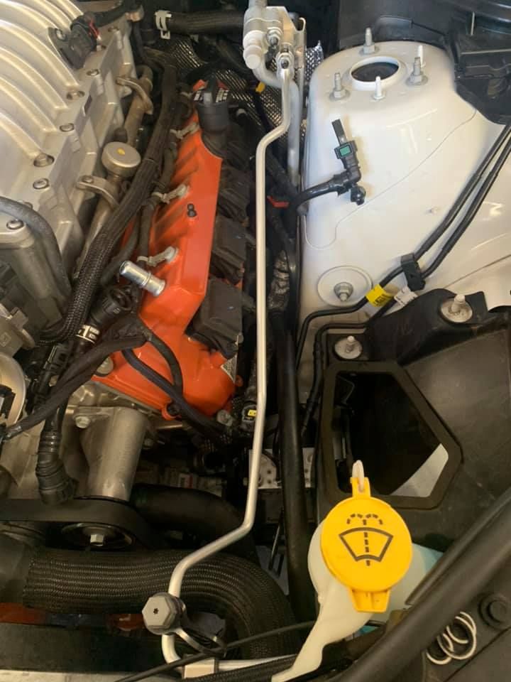 A close up of a car engine with a yellow wiper washer cap