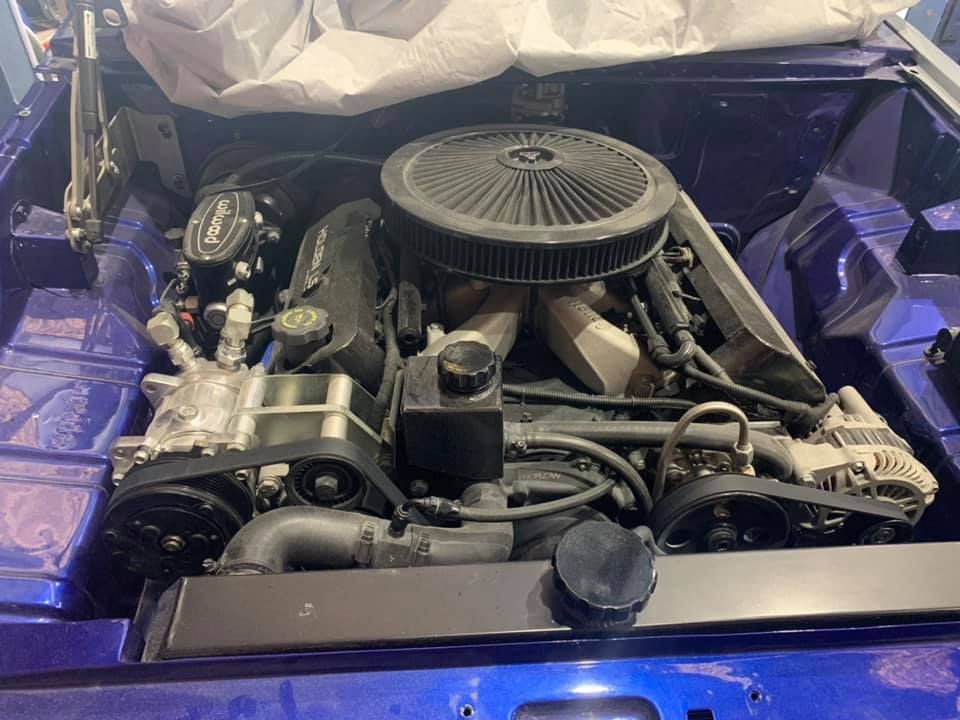 The engine of a blue car is sitting under the hood