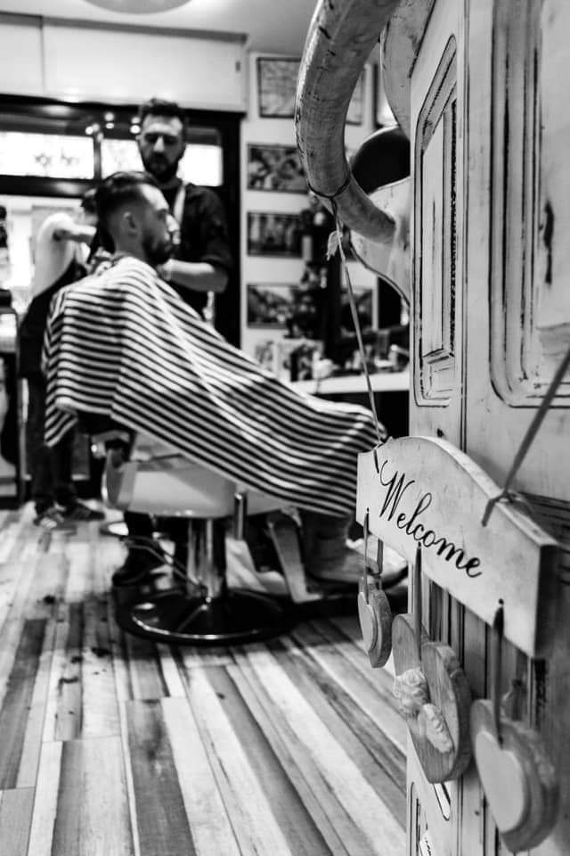 Scena da barbiere con mantello a righe, poltrona da barbiere e un cartello di 