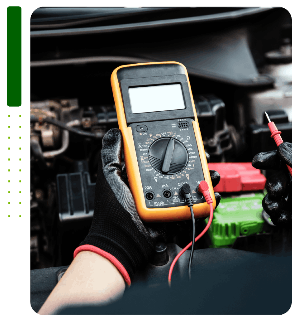 A person is holding a multimeter in front of a car engine.