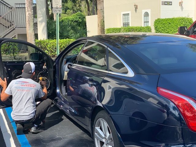 Two men are working on a black car in a parking lot.