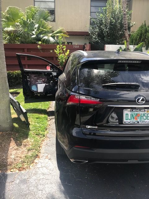 A black lexus is parked in a driveway with its doors open
