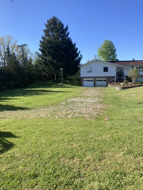 A house with two garages and a large lawn in front of it