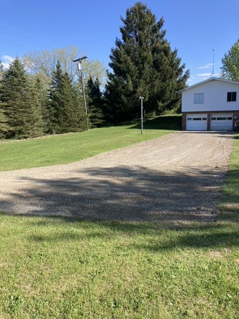 A dirt road leading to a house with two garage doors