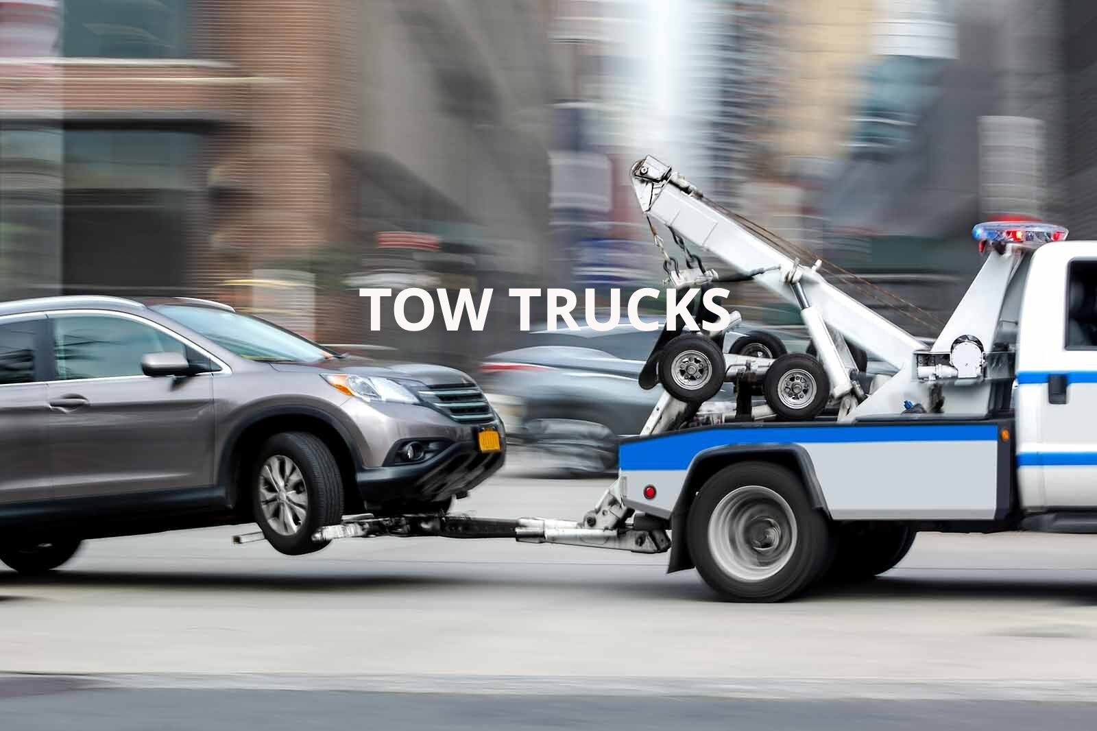 A tow truck is towing a car on a city street.