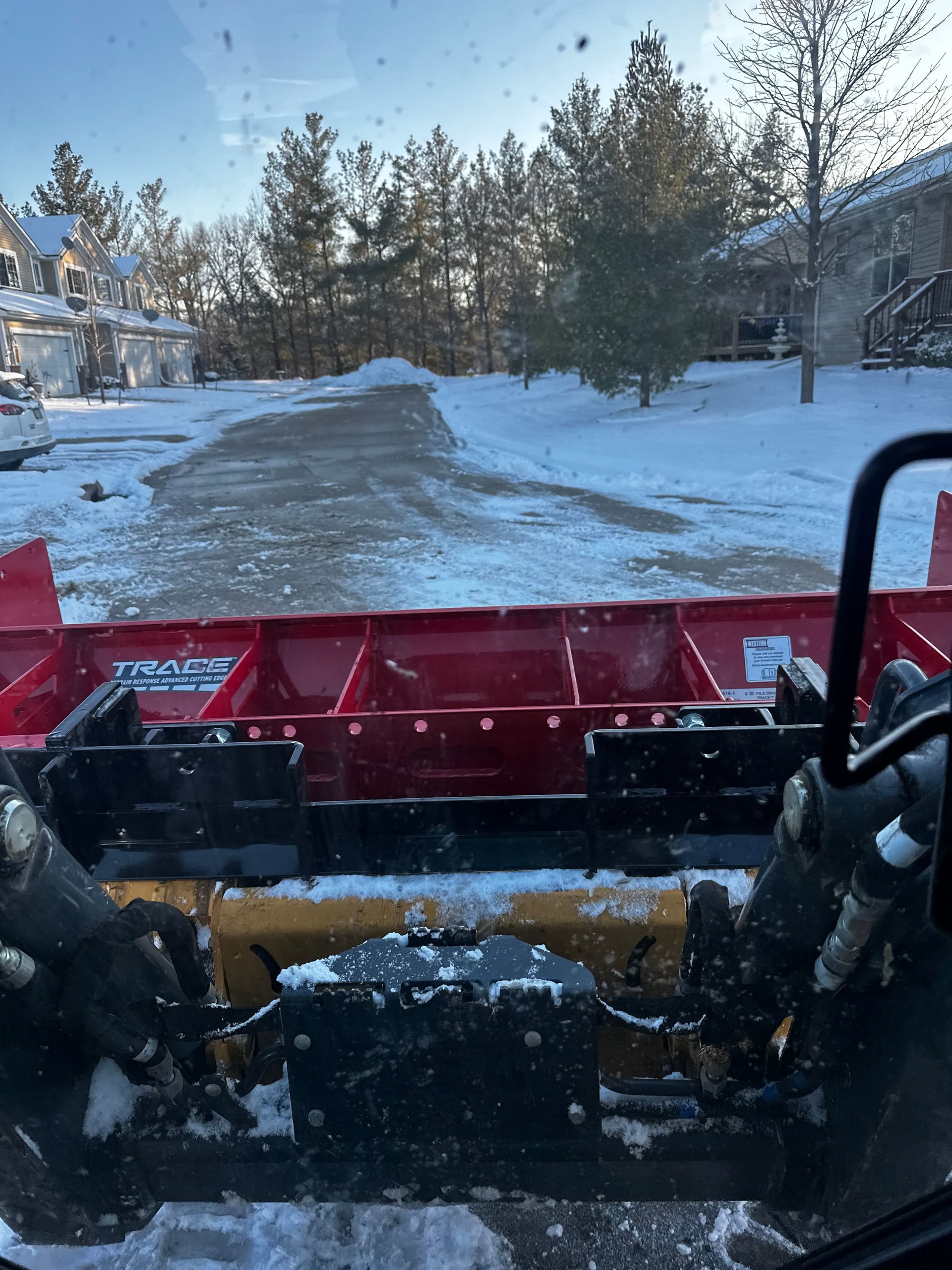 A snow plow is clearing snow from a driveway