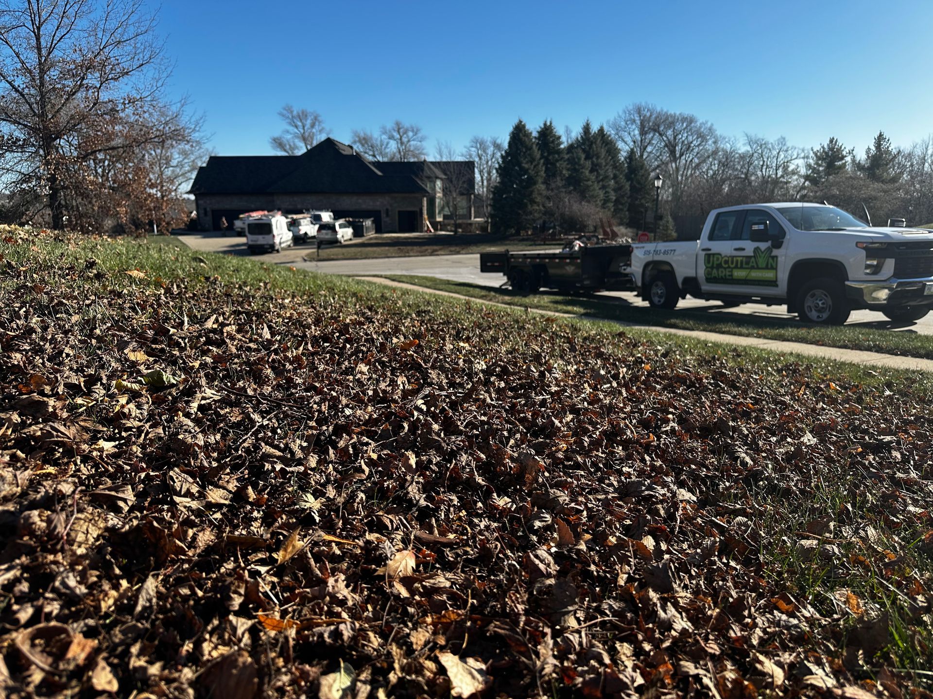 A truck is parked on the side of the road next to a pile of leaves.