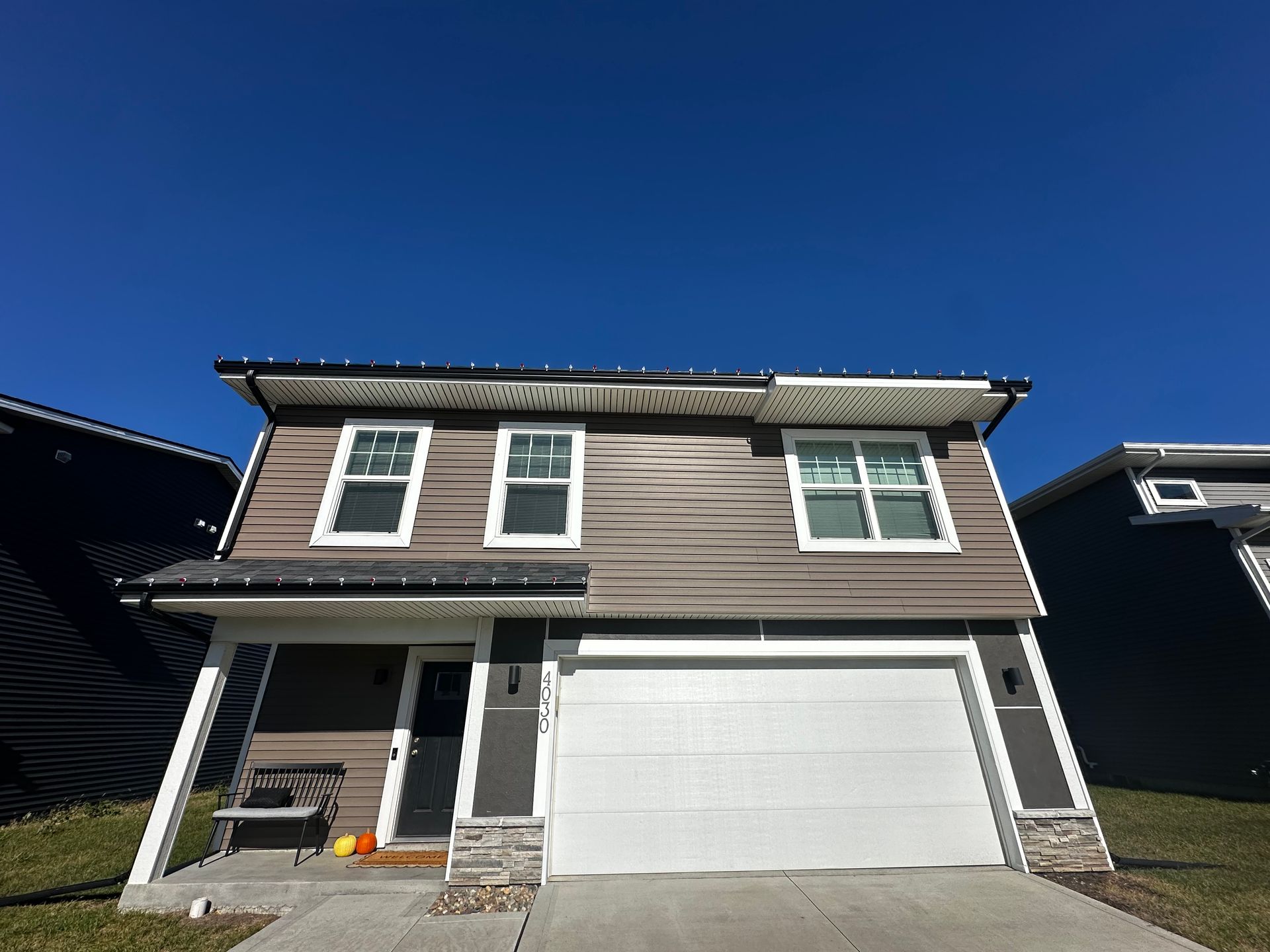A house with a white garage door and a blue sky in the background.