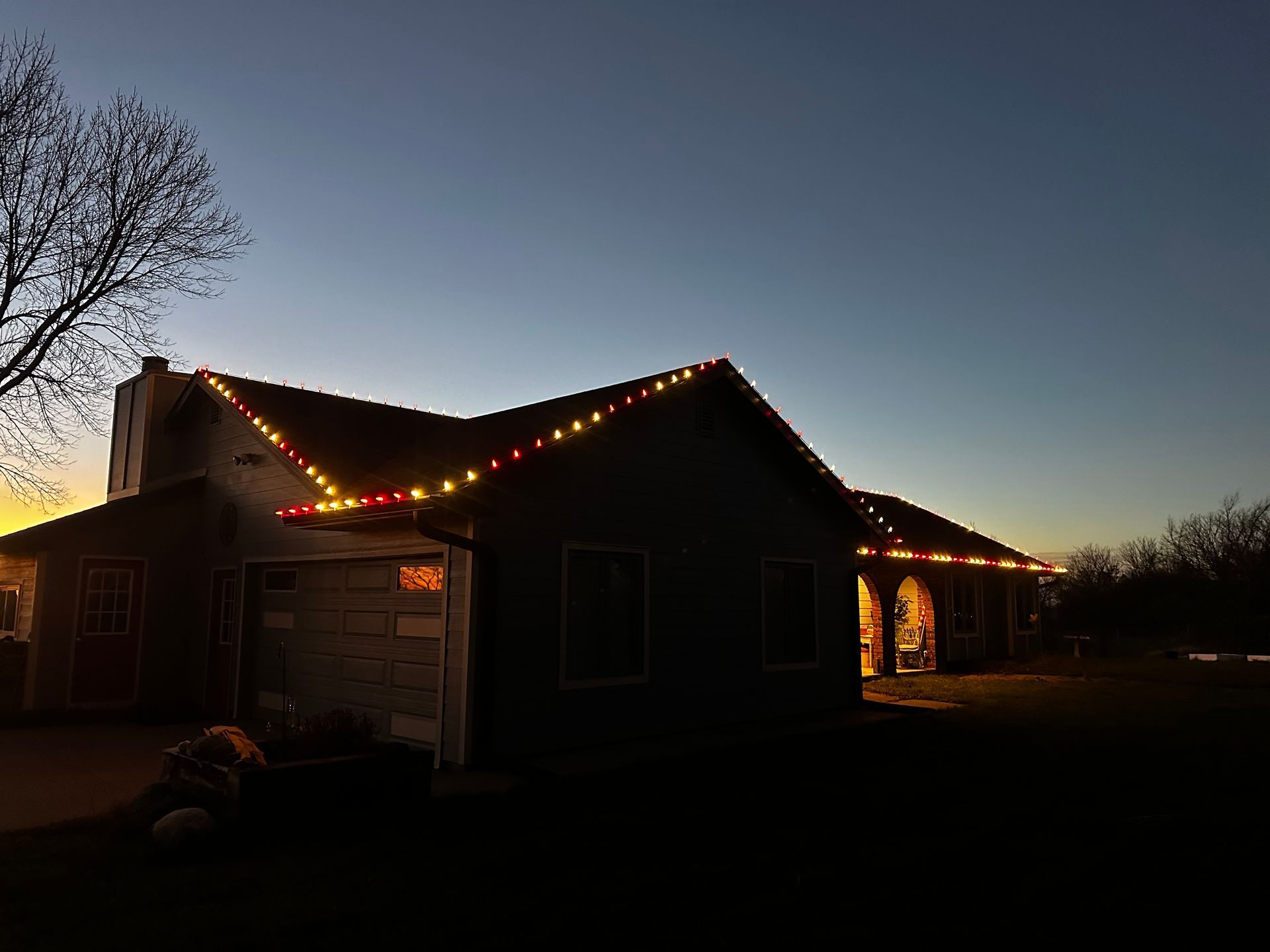 A house with christmas lights on the roof at night.
