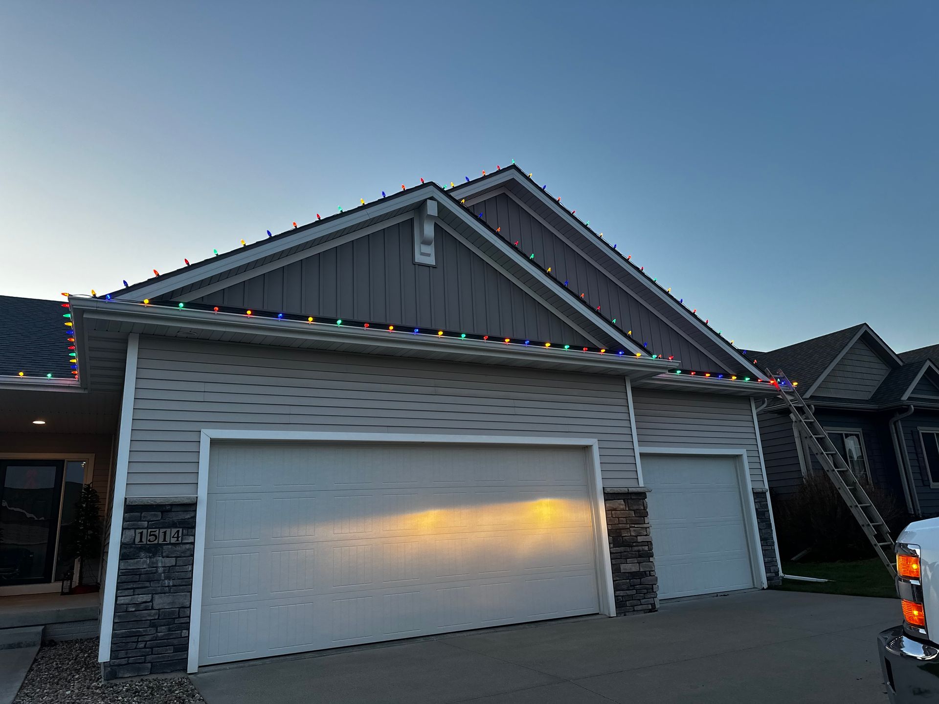 A house with a truck parked in front of it is decorated with christmas lights.