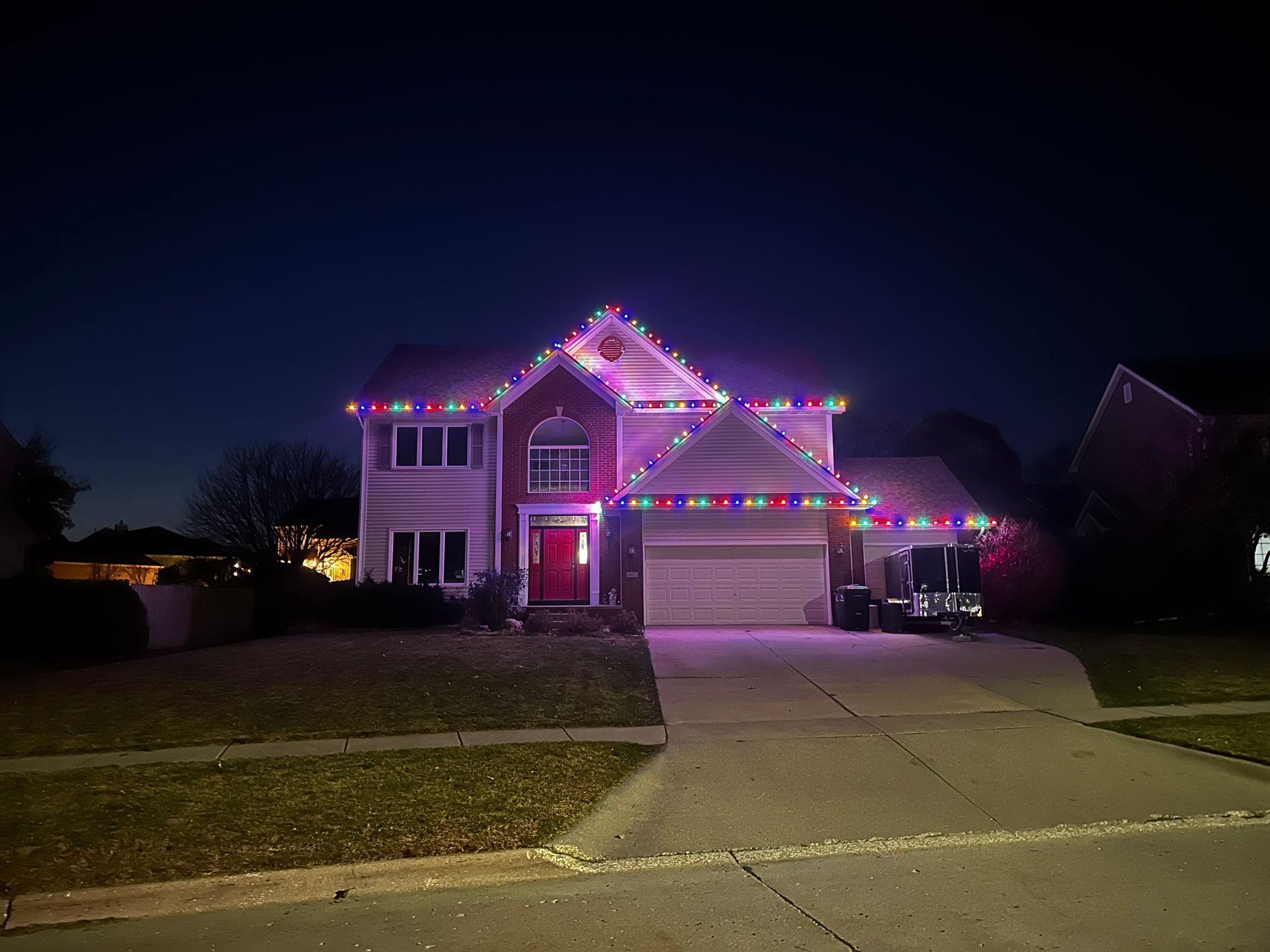 A house with christmas lights on it is lit up at night.