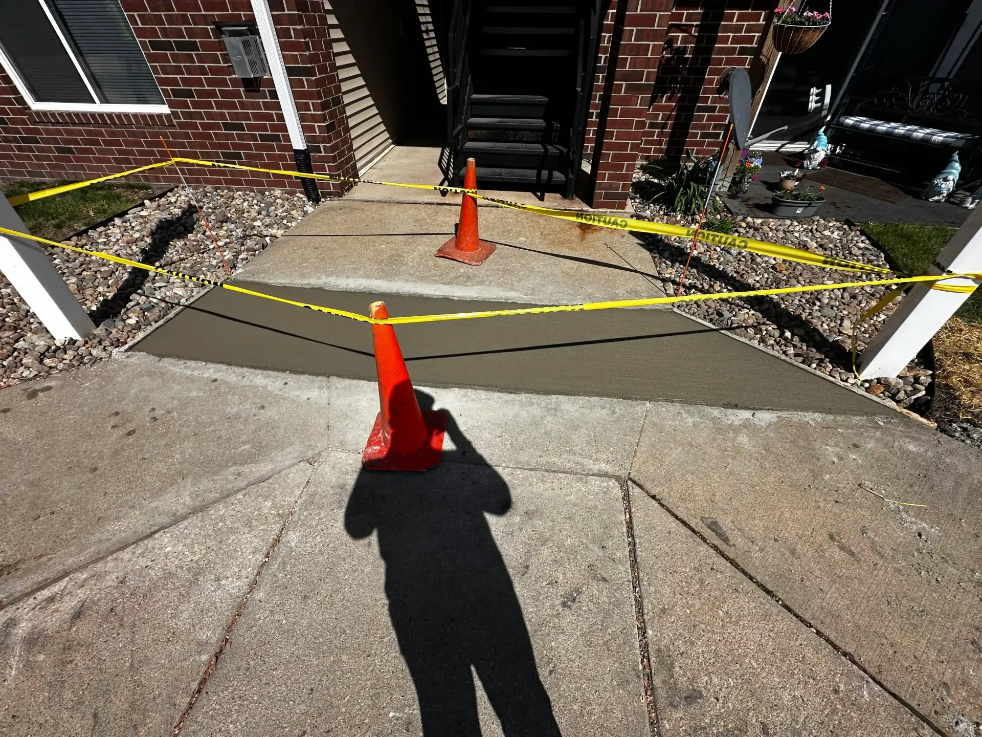 A shadow of a person is cast on a concrete walkway