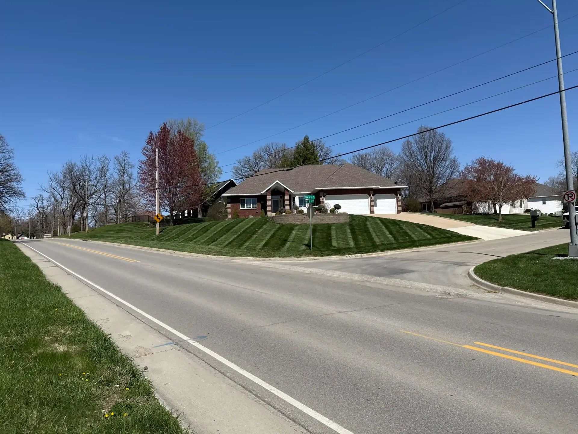 A house is sitting on top of a lush green hill next to a road.