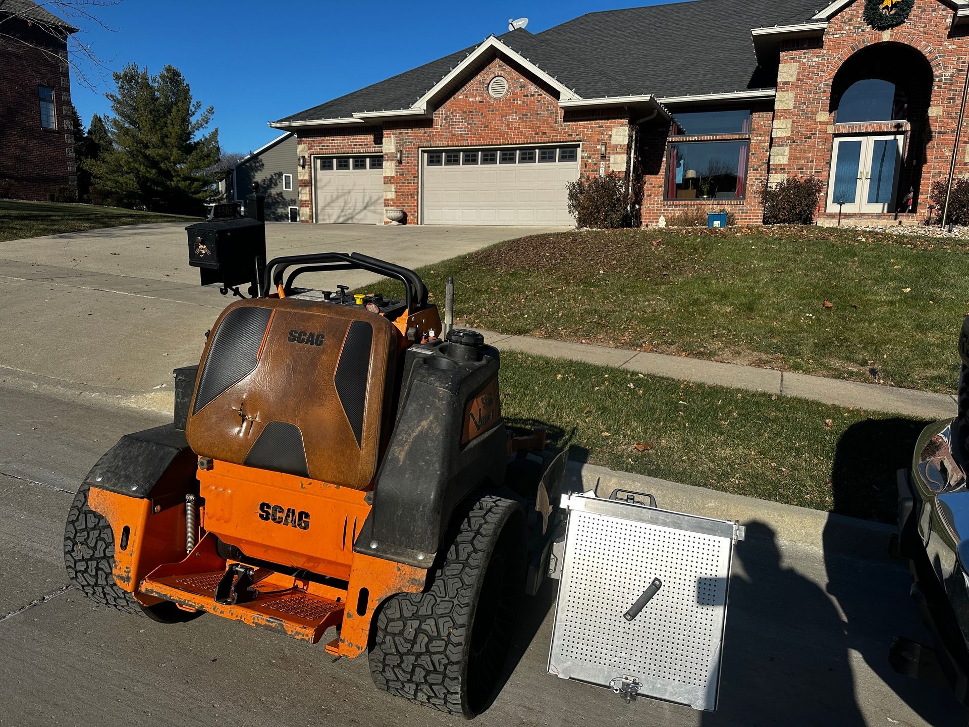 A scpac lawn mower is parked in front of a brick house