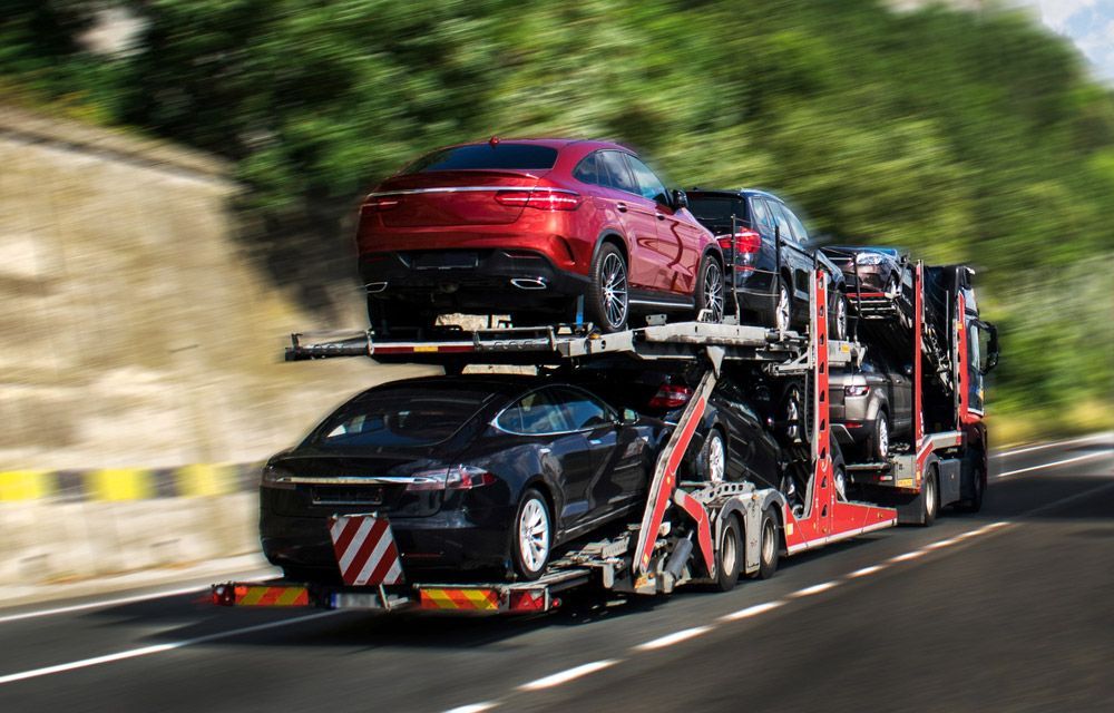 A Car Transporter Is Driving Down a Highway Carrying Cars — Aussie Car Transporters In Welshpool, WA