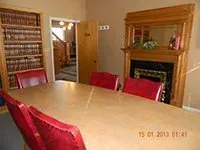 A conference room with a long table and red chairs and a fireplace.