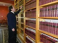A man is standing in front of a bookshelf full of books.