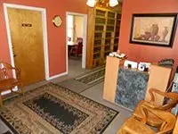 A waiting room with a rug , chairs , and a desk.