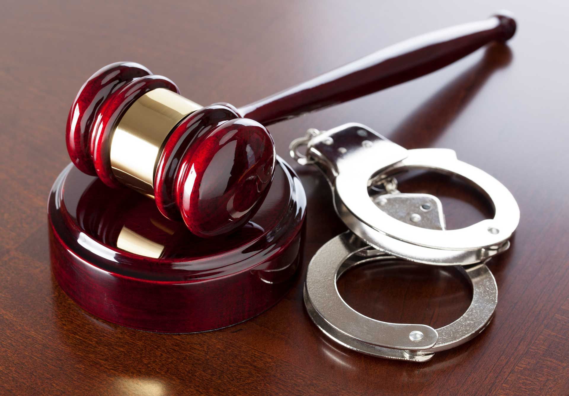 A judge 's gavel and handcuffs on a wooden table