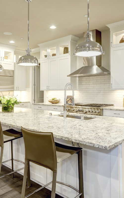 A kitchen with white cabinets , granite counter tops , stainless steel appliances and a large island.