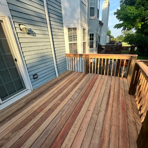 A wooden deck in front of a house with a sliding glass door.