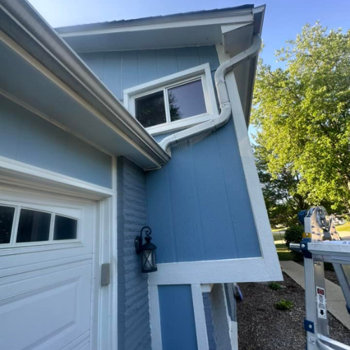 A blue house with white trim and a white garage door