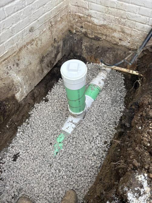 A drain pipe is being installed in a hole in the ground.