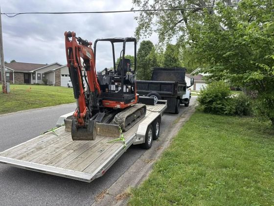 A small excavator is being towed by a trailer.