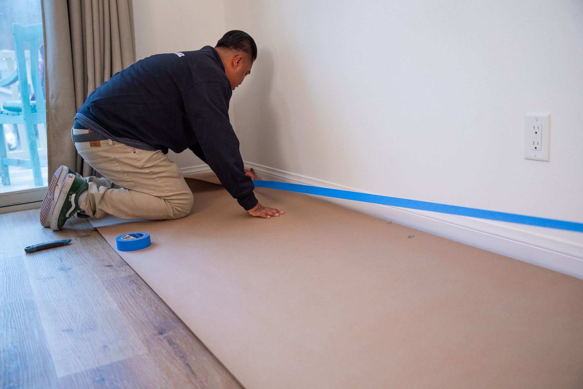 a man is kneeling down on a piece of cardboard .