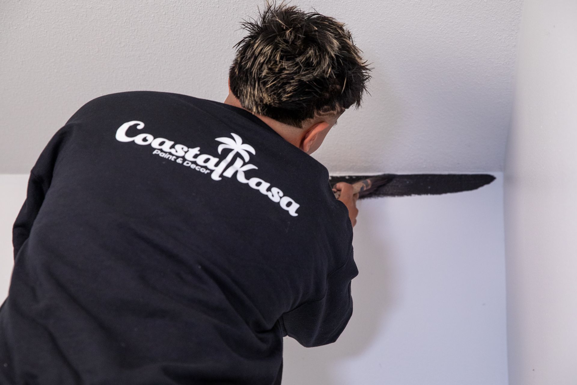a man wearing a coastal kasa shirt is working on a wall