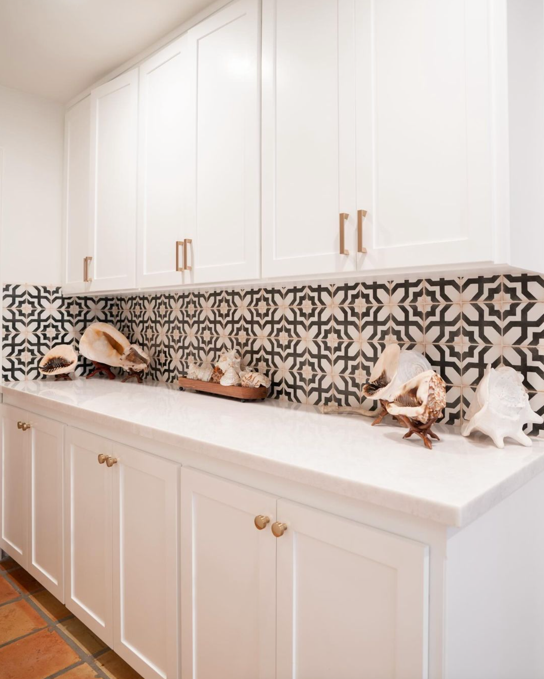 a kitchen with white cabinets and black and white tiles on the wall .