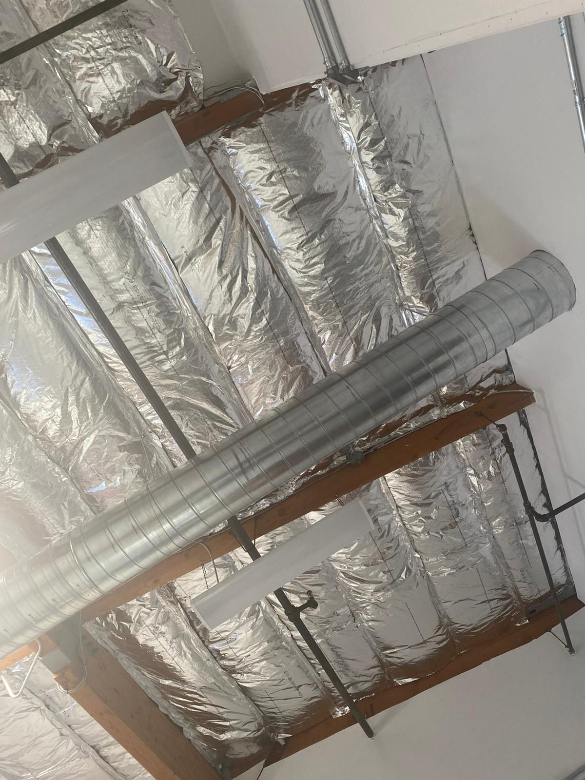 A metal pipe is hanging from the ceiling of a building.