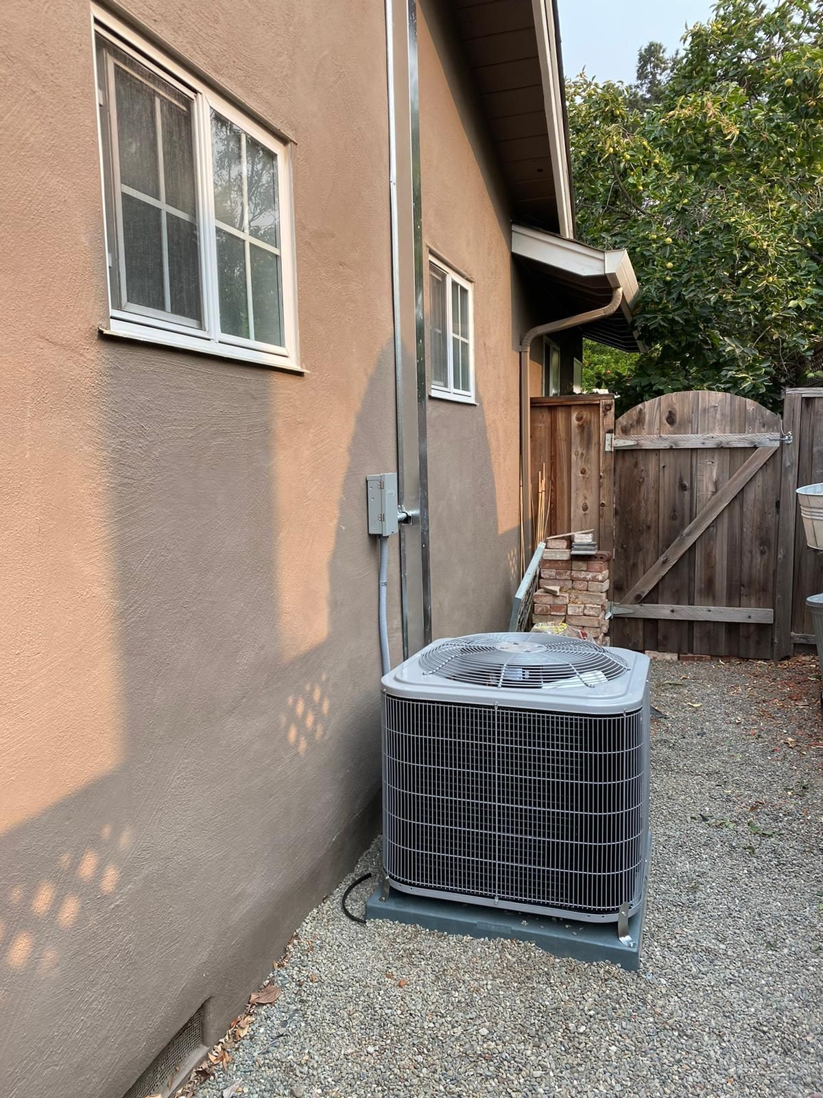 A large air conditioner is sitting on the side of a house.