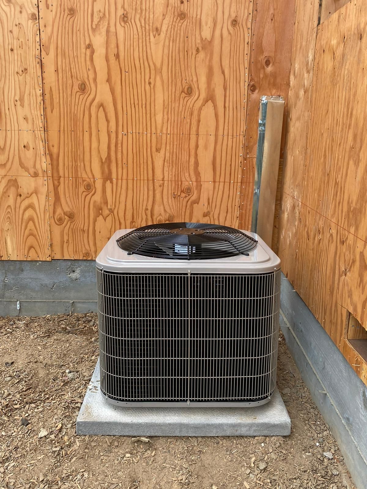A large air conditioner is sitting in a room next to a wooden wall.