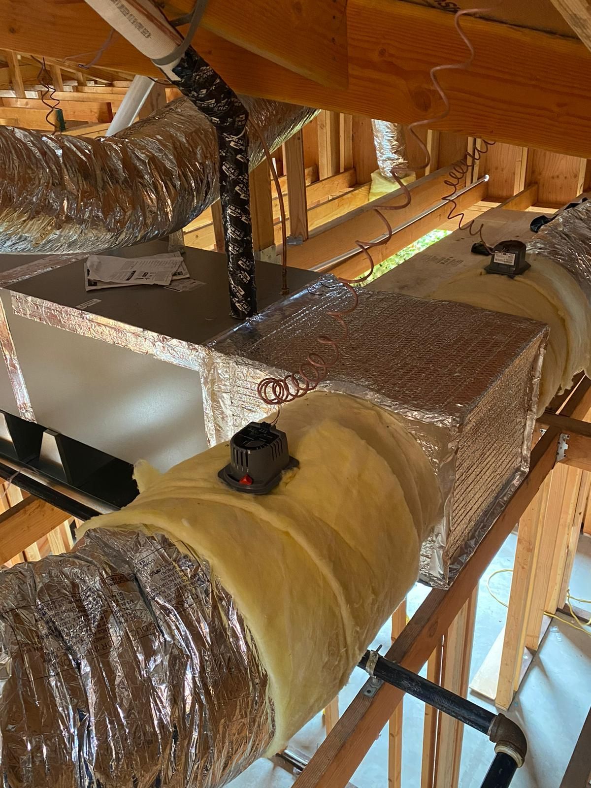 A bunch of ducts are hanging from the ceiling of a building.