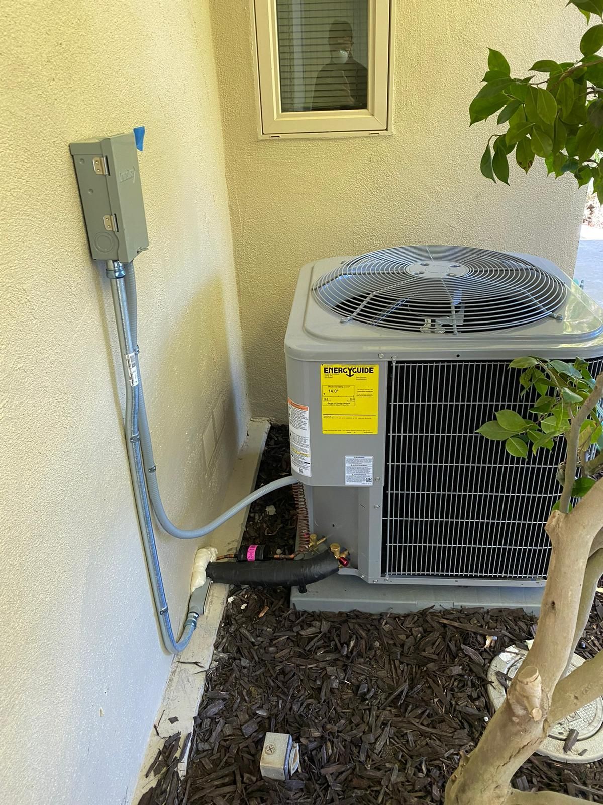 An air conditioner is sitting on the side of a building next to a window.