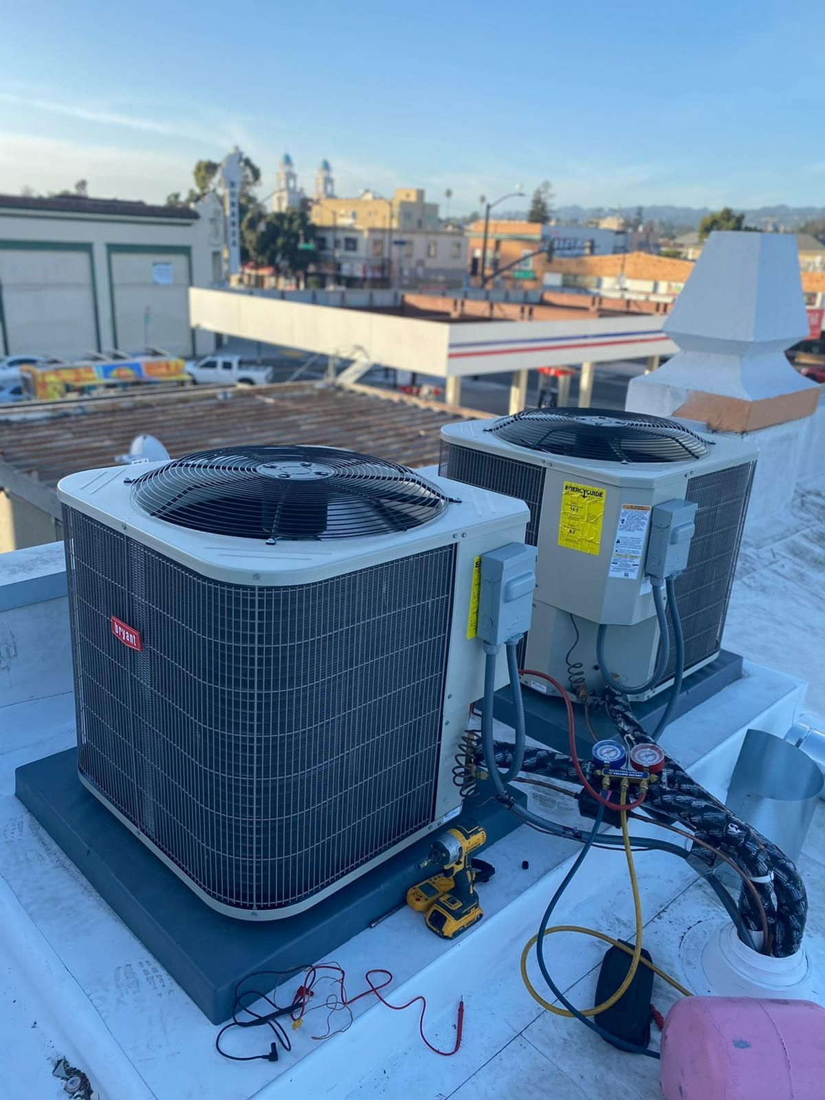 Two air conditioners are sitting on top of a white roof.