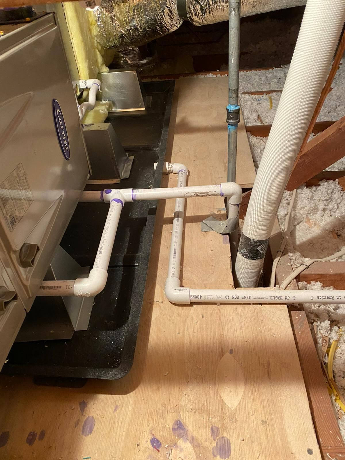 There are a lot of pipes connected to a machine in the attic.