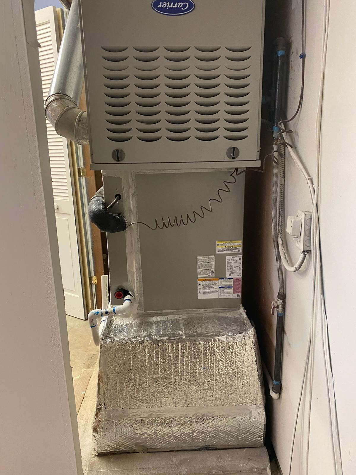 A carrier air conditioner is sitting in a corner of a room next to a wall.